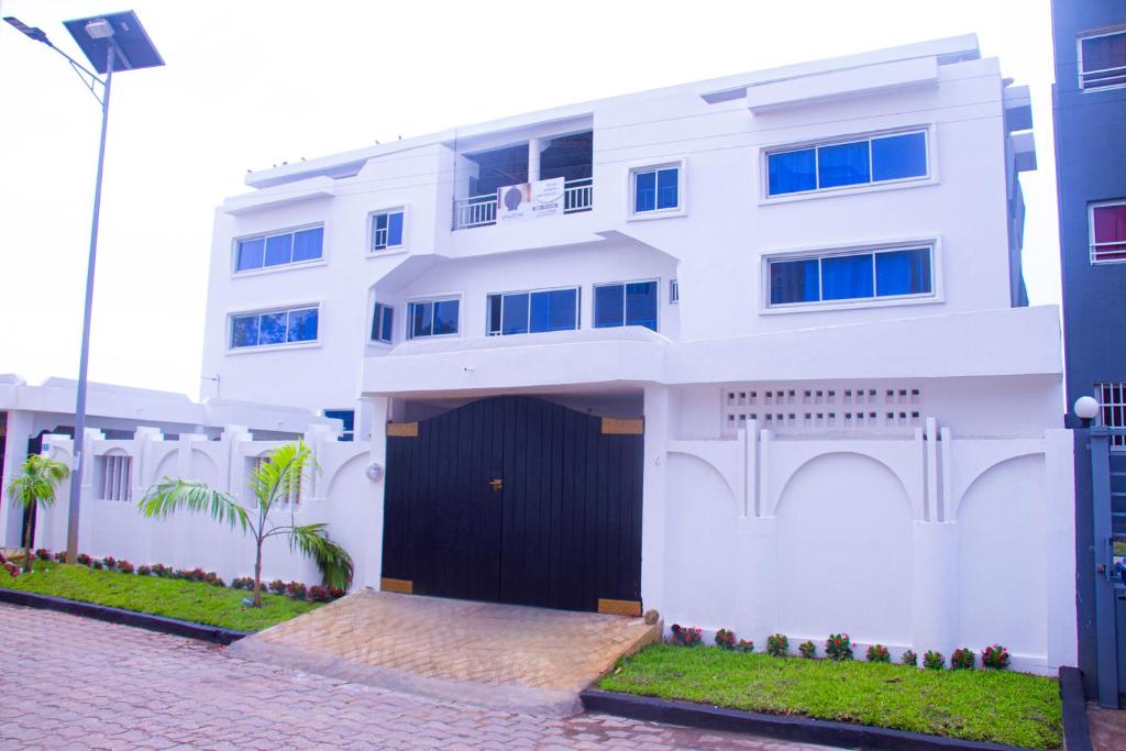 a white house with a black door and a driveway at Hôtel Amazone in Cotonou