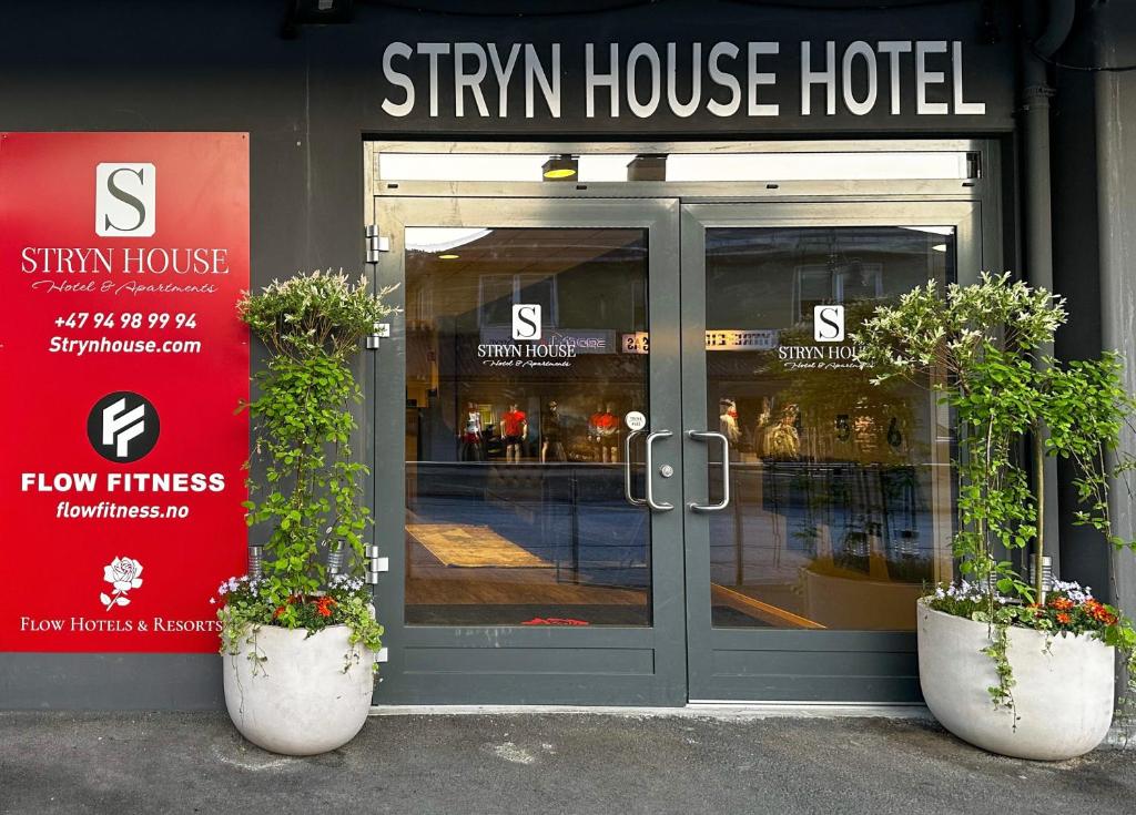 uma frente de loja com dois vasos de plantas na frente da porta em Stryn House - Hotel & Apartments em Stryn