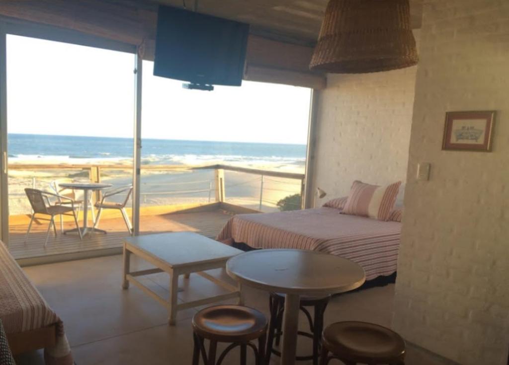 a bedroom with a bed and a balcony with a table and chairs at Miralejos in Punta Del Diablo