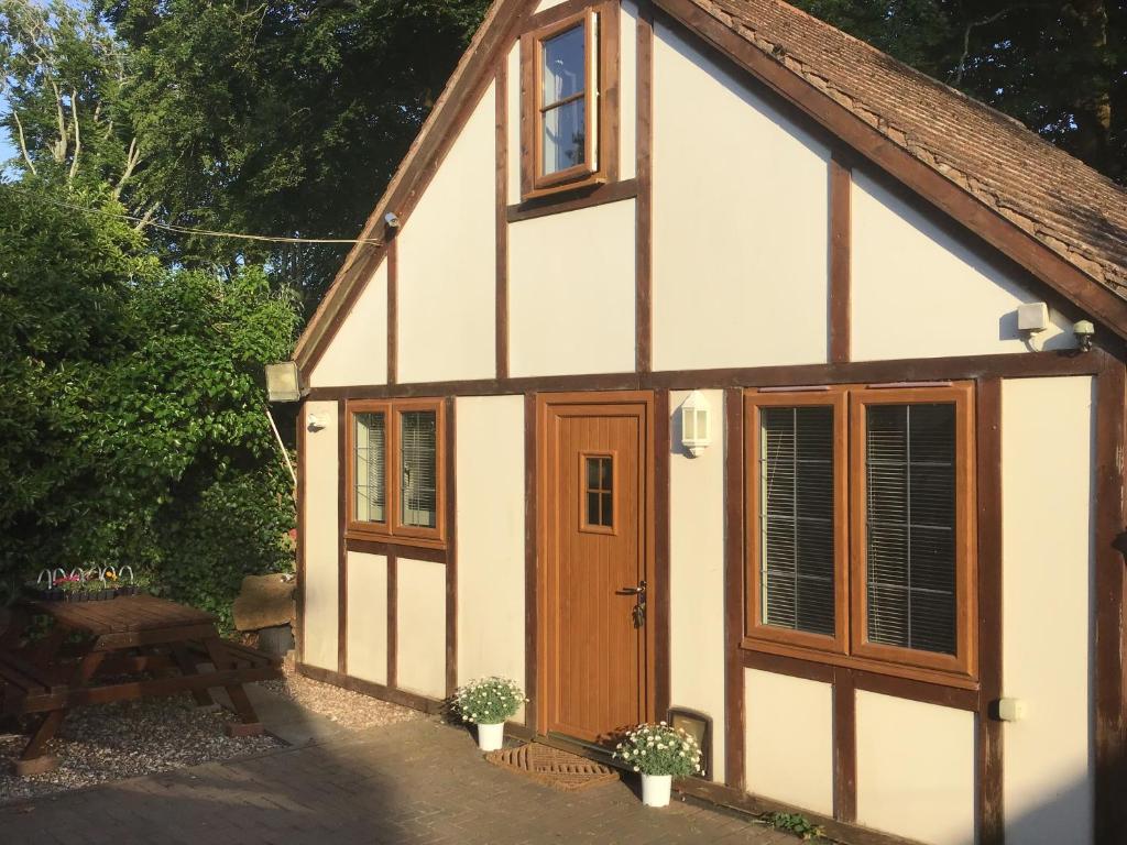 a small house with a wooden door and a table at Little Nest EV Point in Wadebridge