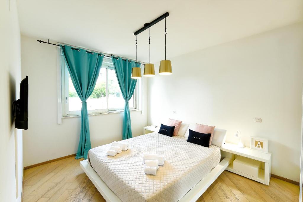 una camera da letto bianca con tende blu e un letto di MIMA61 - Appartamento con giardino e posti auto a 50mt dal centro a Milano Marittima
