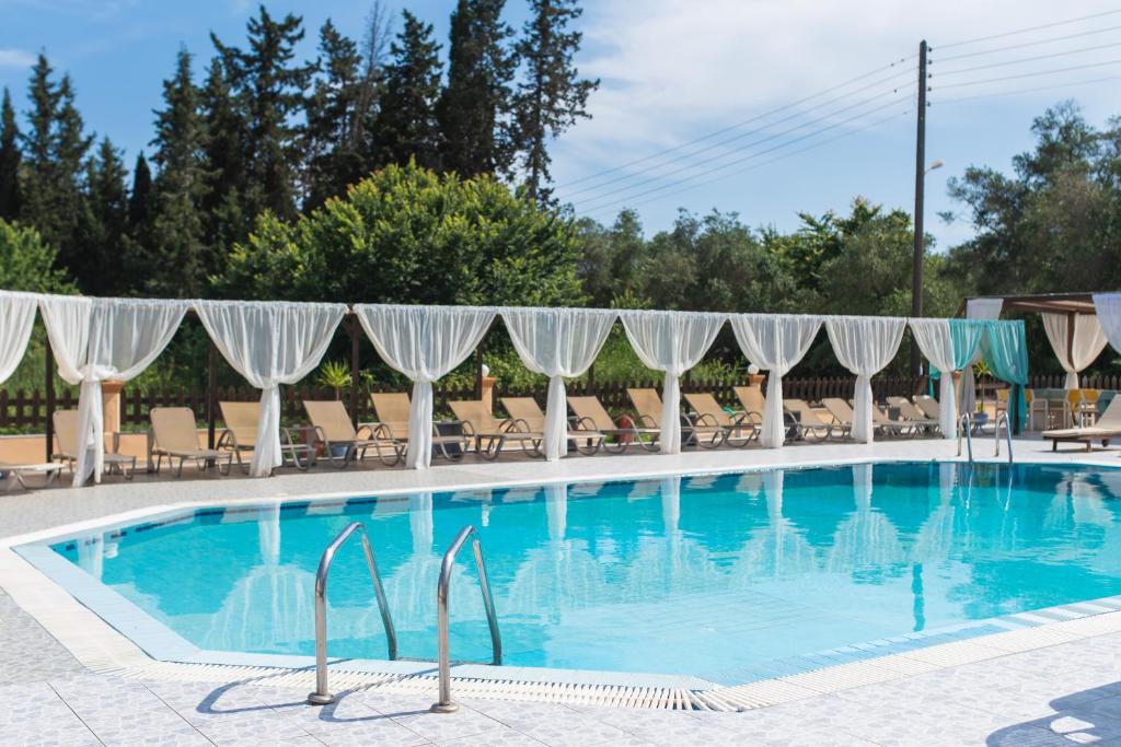 a pool at a hotel with chairs and umbrellas at Sandy Beach Annexe in Kavos