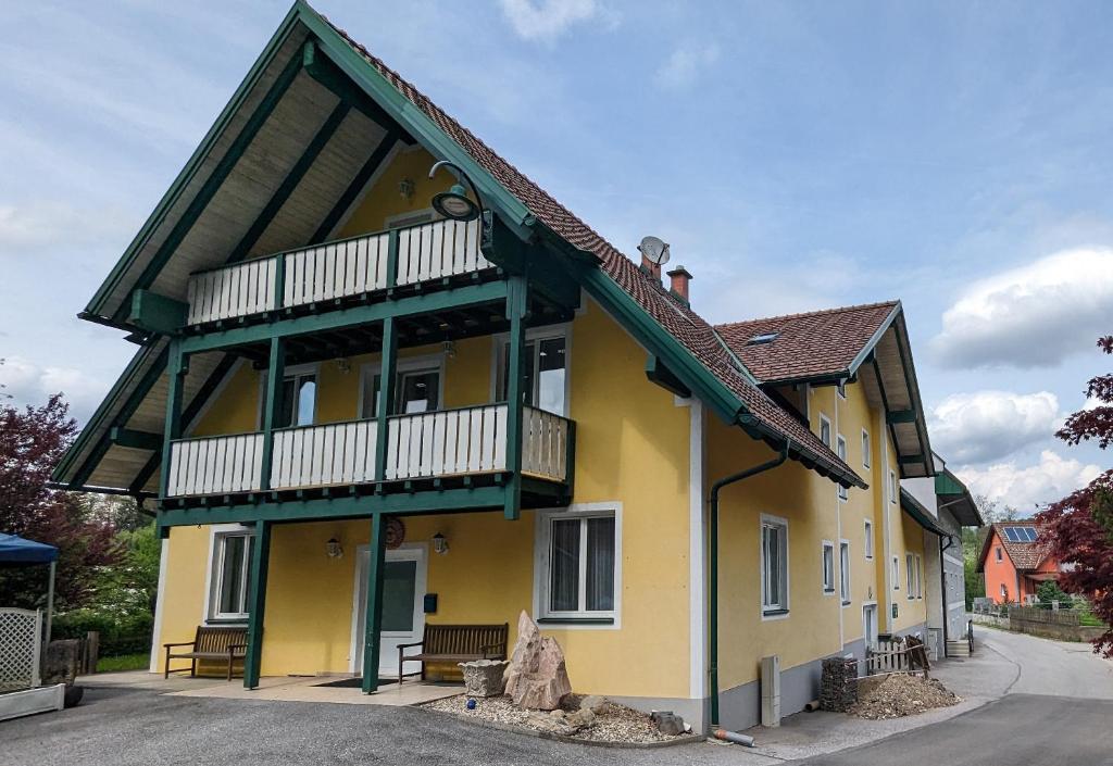 a yellow house with a balcony on a street at Weinloft Ehrenhausen in Ehrenhausen