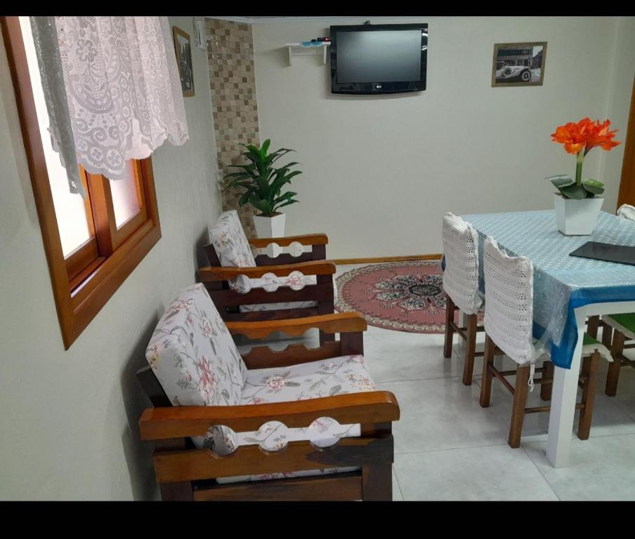 sala de estar con mesa, sillas y TV en Casa e Flat Conforto Gramado, en Gramado