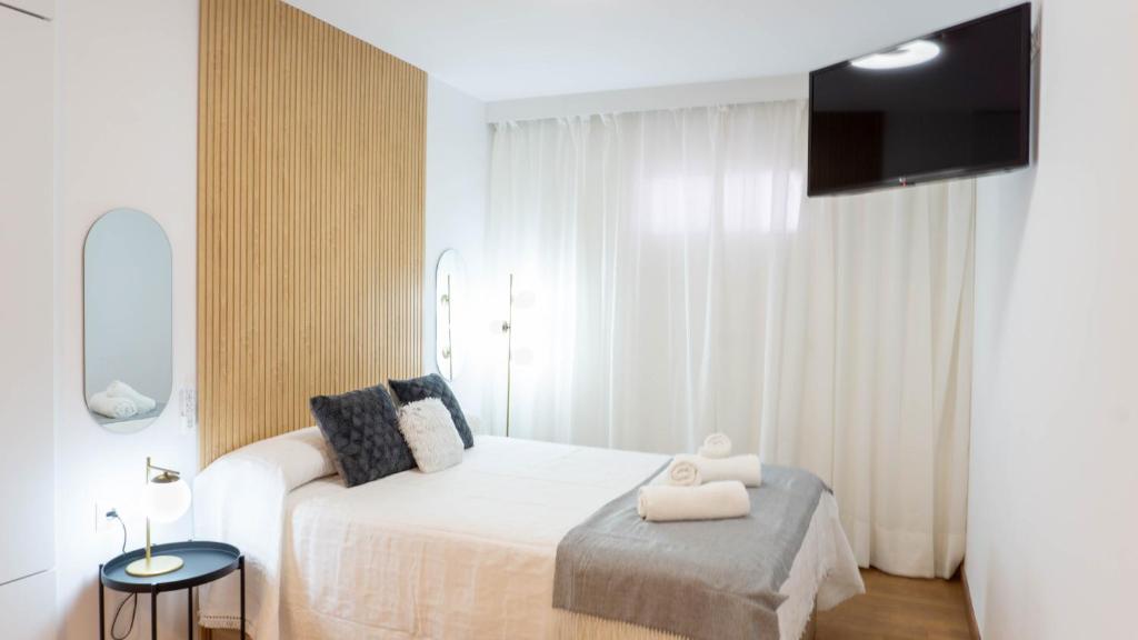 ein weißes Schlafzimmer mit einem weißen Bett und einem TV in der Unterkunft Pizarro Apartment Malaga in Torremolinos