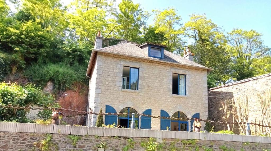 uma velha casa de pedra com uma cerca em frente em Les bords de Rance em Dinan