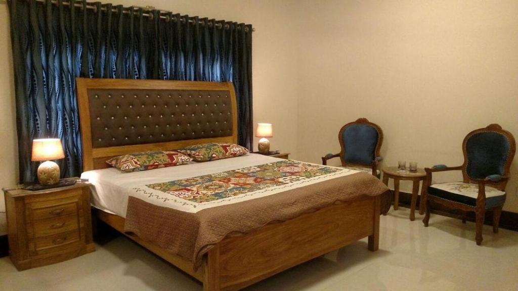 a bedroom with a large bed and two chairs at Hotel Inn PECHS in Karachi