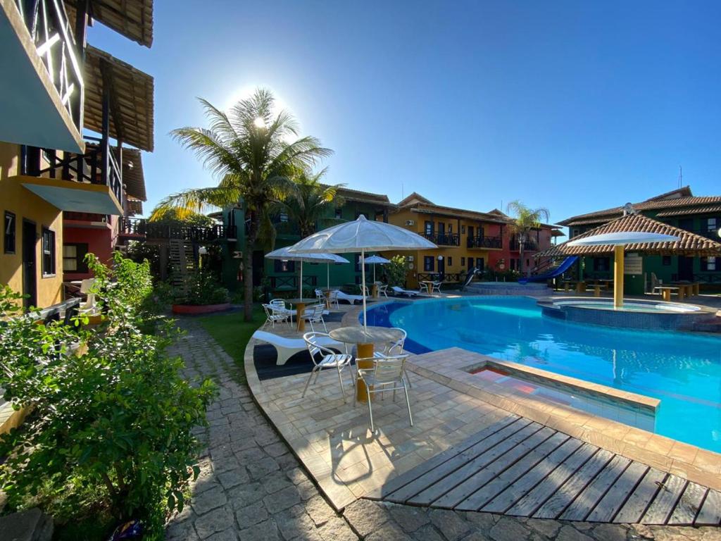 a pool with a table and an umbrella next to a building at Costa Marlin Hotel in Guriri