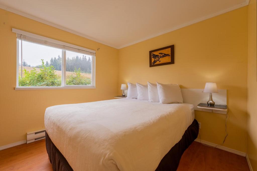 a bedroom with a large white bed with a window at The Cabins at Alert Bay in Alert Bay