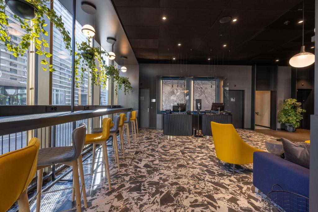 a restaurant with yellow chairs and a bar at Radisson Hotel & Suites Zurich in Opfikon