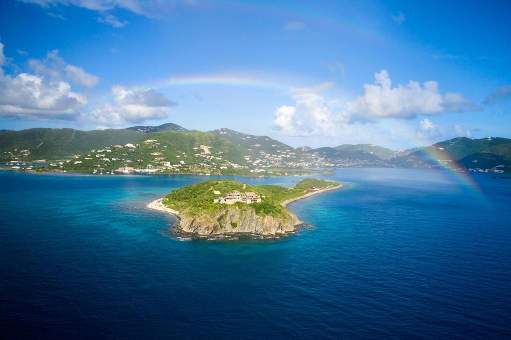an island in the ocean with a rainbow in the sky at The Aerial, BVI All-Inclusive Private Island in Tortola Island