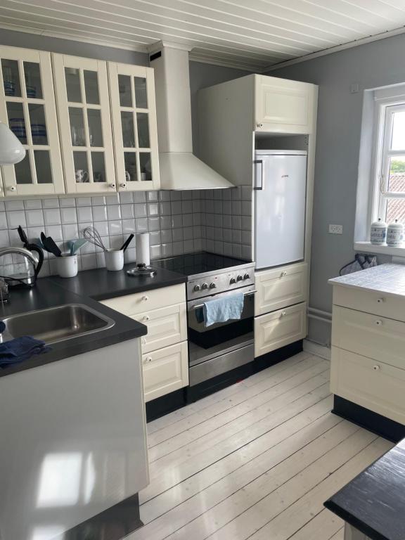 a kitchen with white cabinets and a stove top oven at ØsterLars blue Pearl in Gudhjem