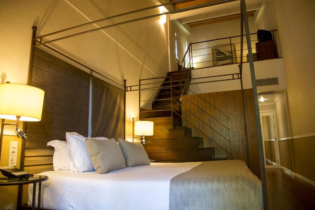 a bedroom with a bed with a staircase behind it at Hotel Nuevo Portil Golf in El Rompido