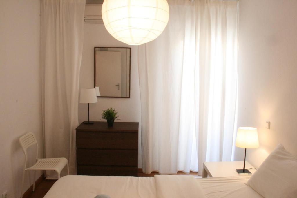 a bedroom with a bed and a window with white curtains at Campo Grande Residence in Lisbon