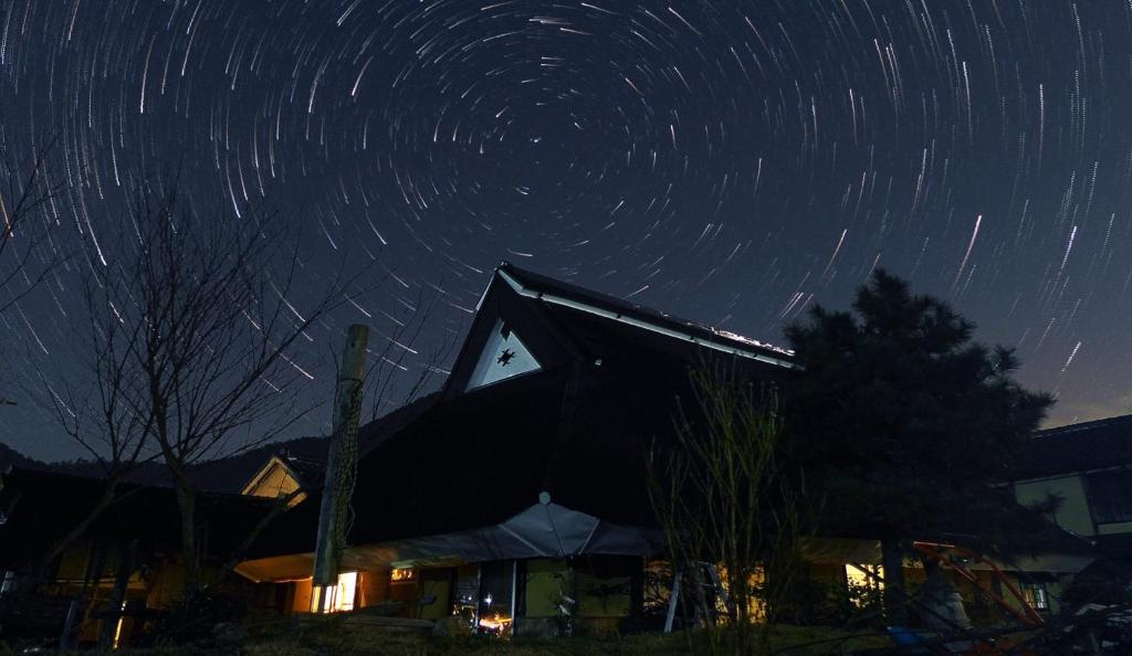 a star trails in the night sky over a building at 古民家の宿 ふるま家 Furumaya House Gastronomic Farmstay in Deep Kyoto in Fukuchiyama