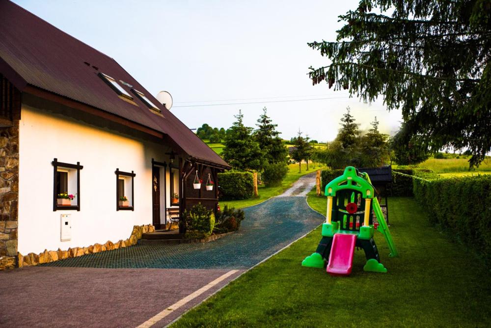 een speeltuin in het gras naast een huis bij Agronoclegi ,,Na Równi" 535-950-405 in Mchawa