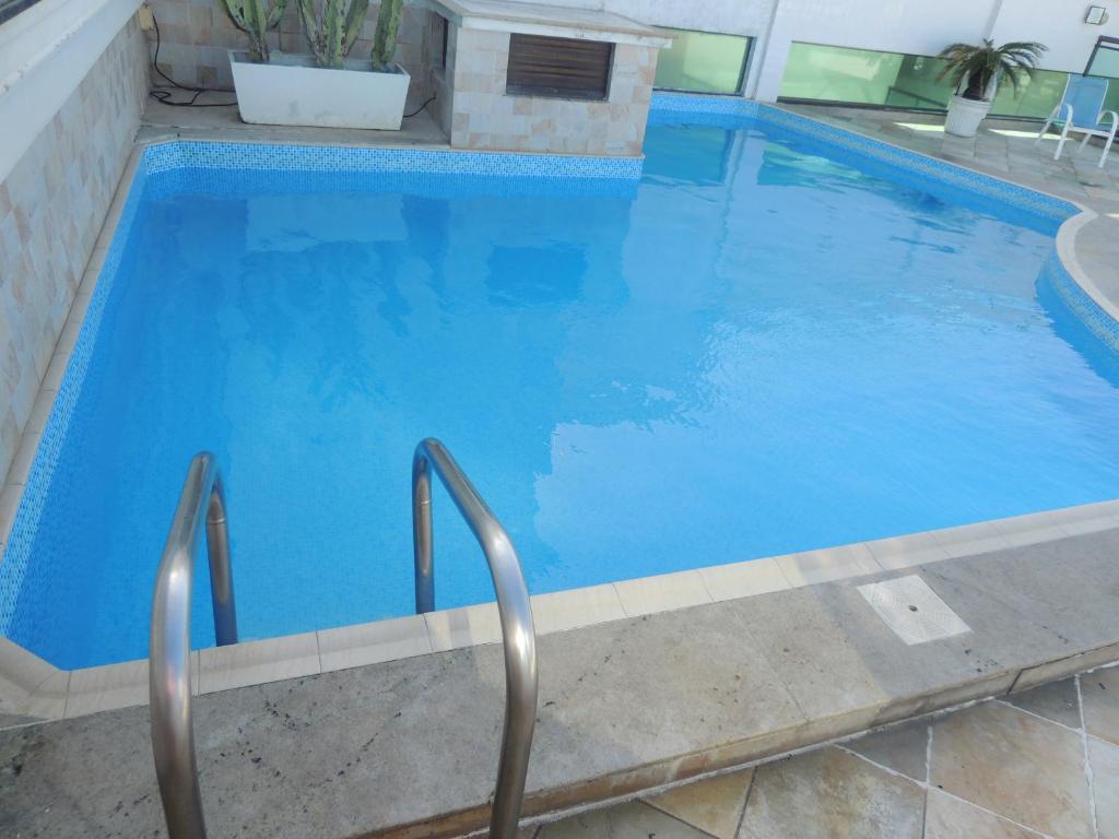 a large blue swimming pool with blue water at Loft Com Vista Para O Mar in Arraial do Cabo