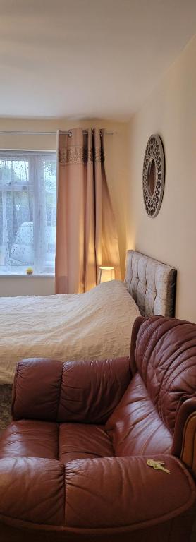 a bedroom with a bed and a leather couch at Lovely studio flat in Reading