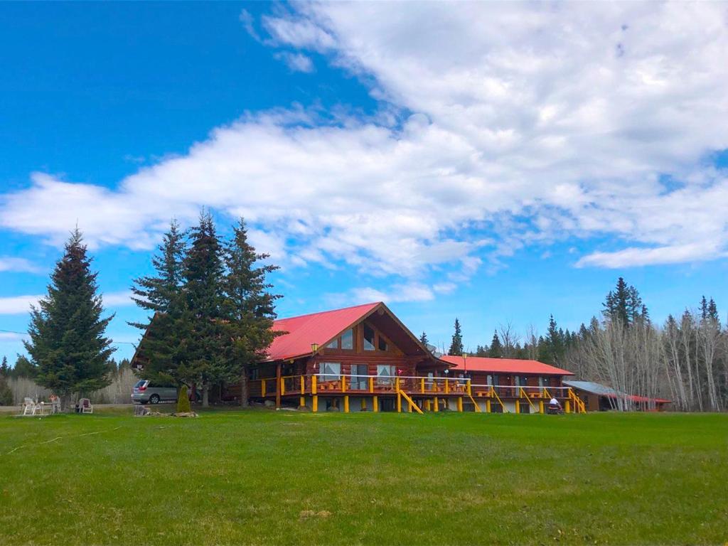 a large house with a red roof on a green field at Cariboo Log Guest House in Lac La Hache