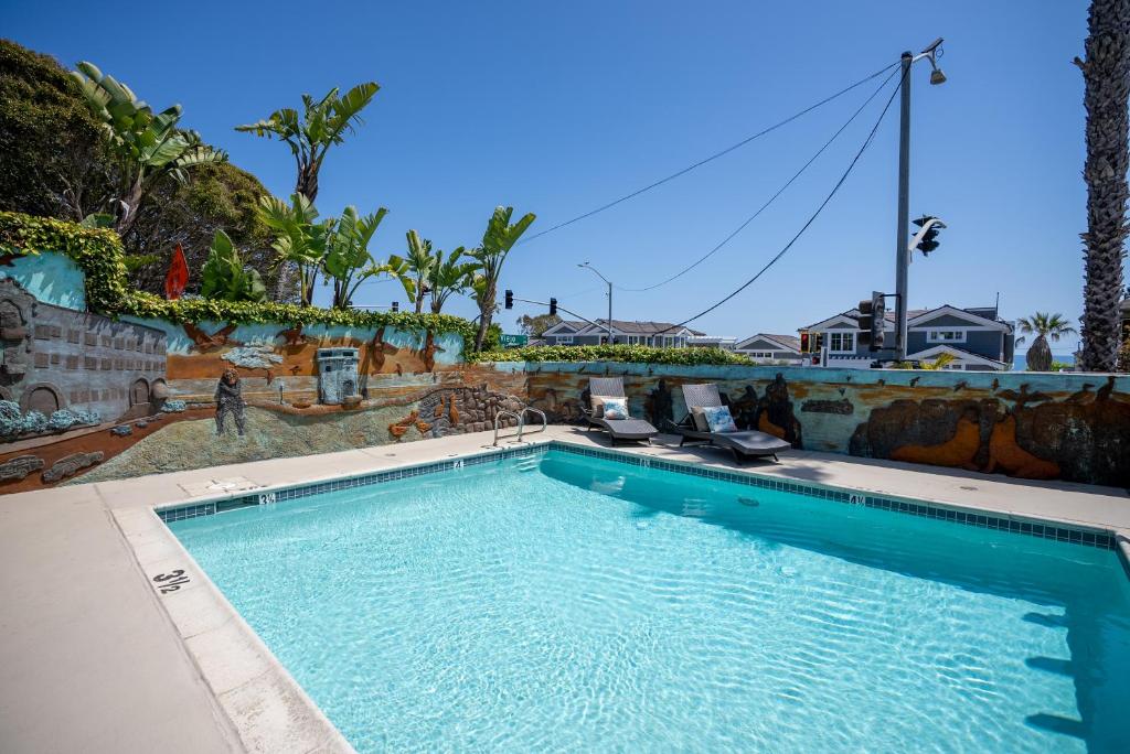 a large swimming pool with two lounge chairs in front of a house at Art Hotel Laguna Beach in Laguna Beach