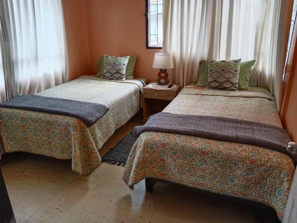 a room with two beds and a lamp on a table at Tu Jardín Secreto in La Serena