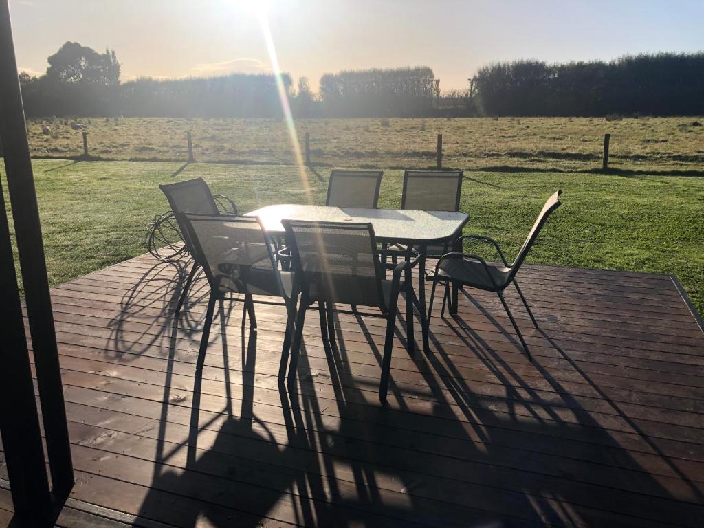 a table and chairs on a deck with a field at Cute Cottage Close to Town in Hastings