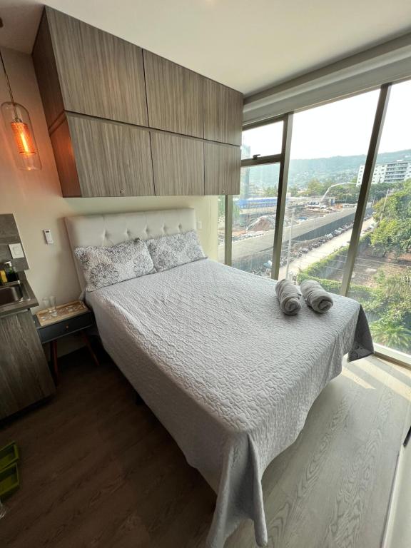 sypialnia z białym łóżkiem i dużym oknem w obiekcie Moderno y Céntrico Aparta-Estudio w mieście Tegucigalpa