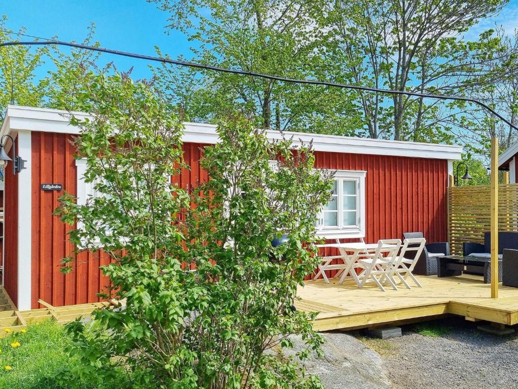 a red tiny house with a deck and a table at 4 person holiday home in GRISSLEHAMN in Grisslehamn