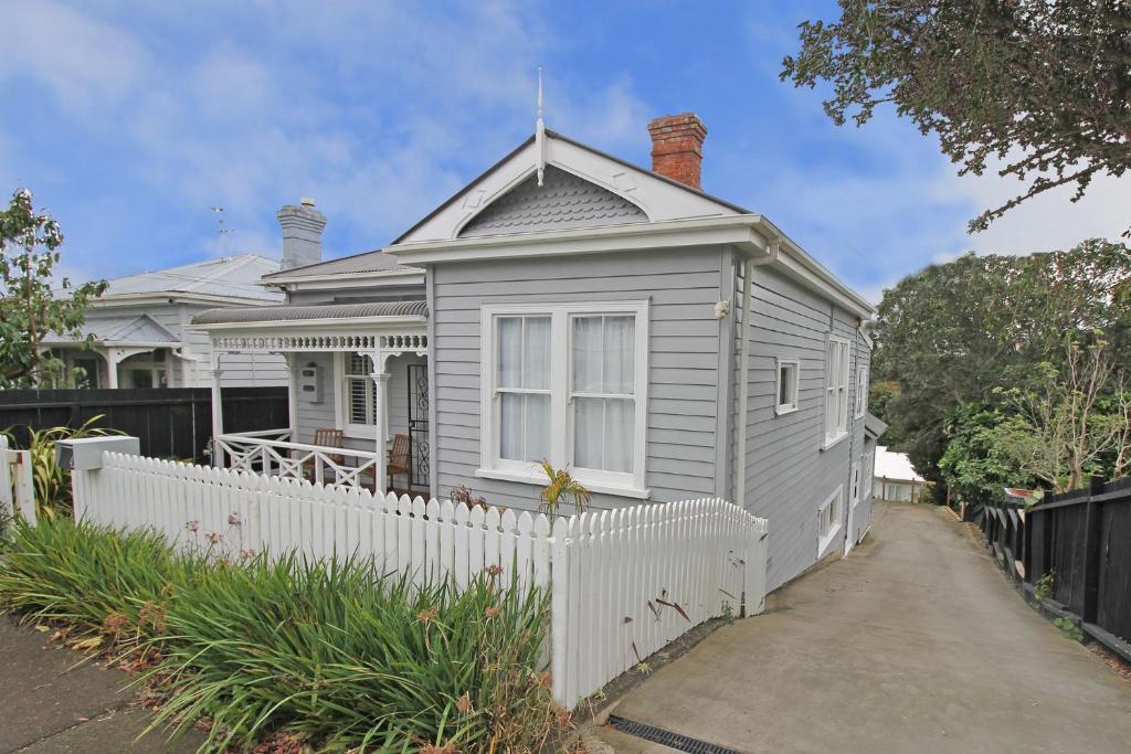 una casa blanca con una valla blanca delante de ella en 2 Bed Apartment in Kingsland - FREE WIFI and parking en Auckland