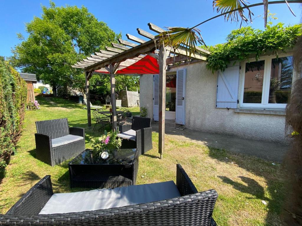 um quintal com uma mesa e cadeiras e uma pérgola em Charming holiday home in a quiet location, near the coast, 2 bicycles em Donville-les-Bains