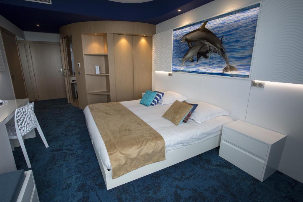 a bedroom with a bed and a picture of a dolphin at Marineland Hôtel in Antibes