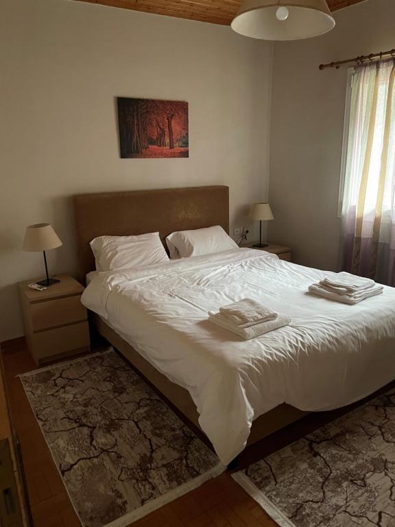 a bedroom with a large bed with white sheets and pillows at Thanasis house in Dimitsana