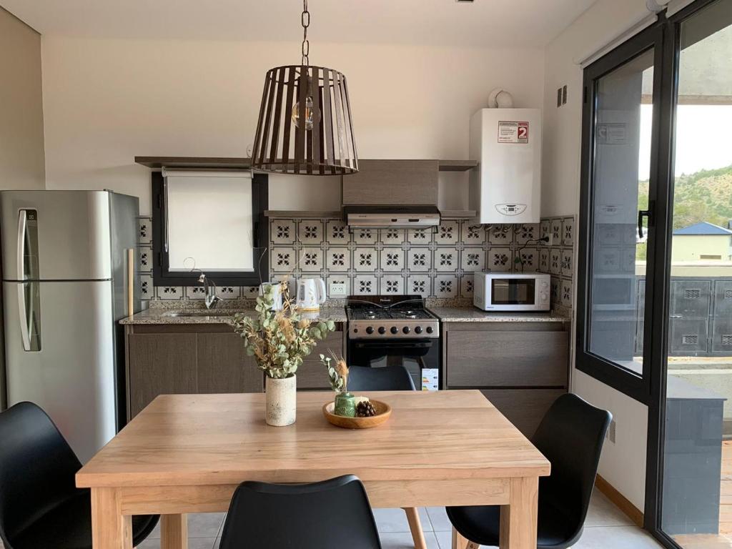 a kitchen with a wooden table and black chairs at Aire de Chapelco in San Martín de los Andes