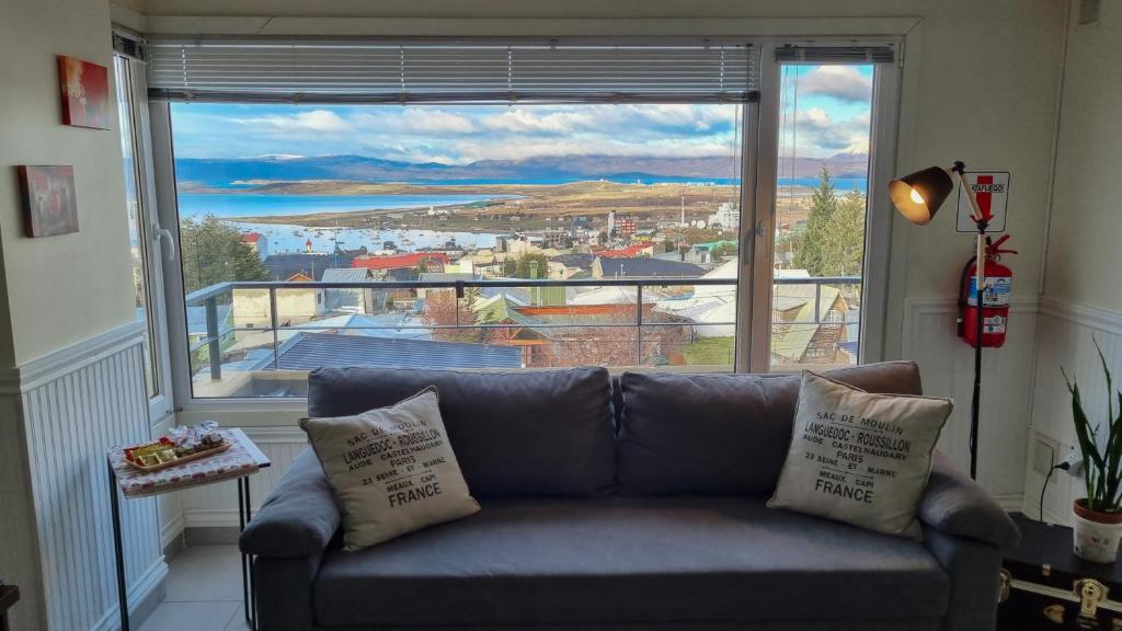 a couch in a living room with a large window at Waia Apartments in Ushuaia
