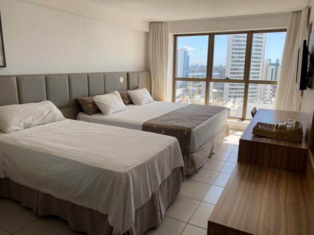 Habitación de hotel con 2 camas y ventana grande. en BEIRA MAR- FLAT EXECUTIVE, en Recife
