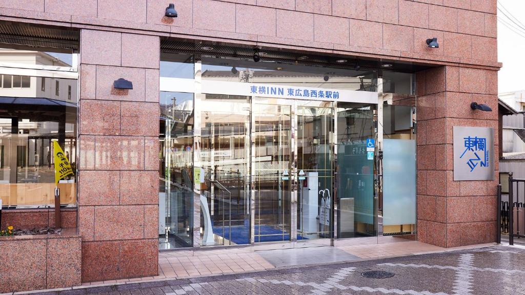 a building with glass doors in a city at Toyoko Inn Higashi-hiroshima Saijo Ekimae in Higashihiroshima