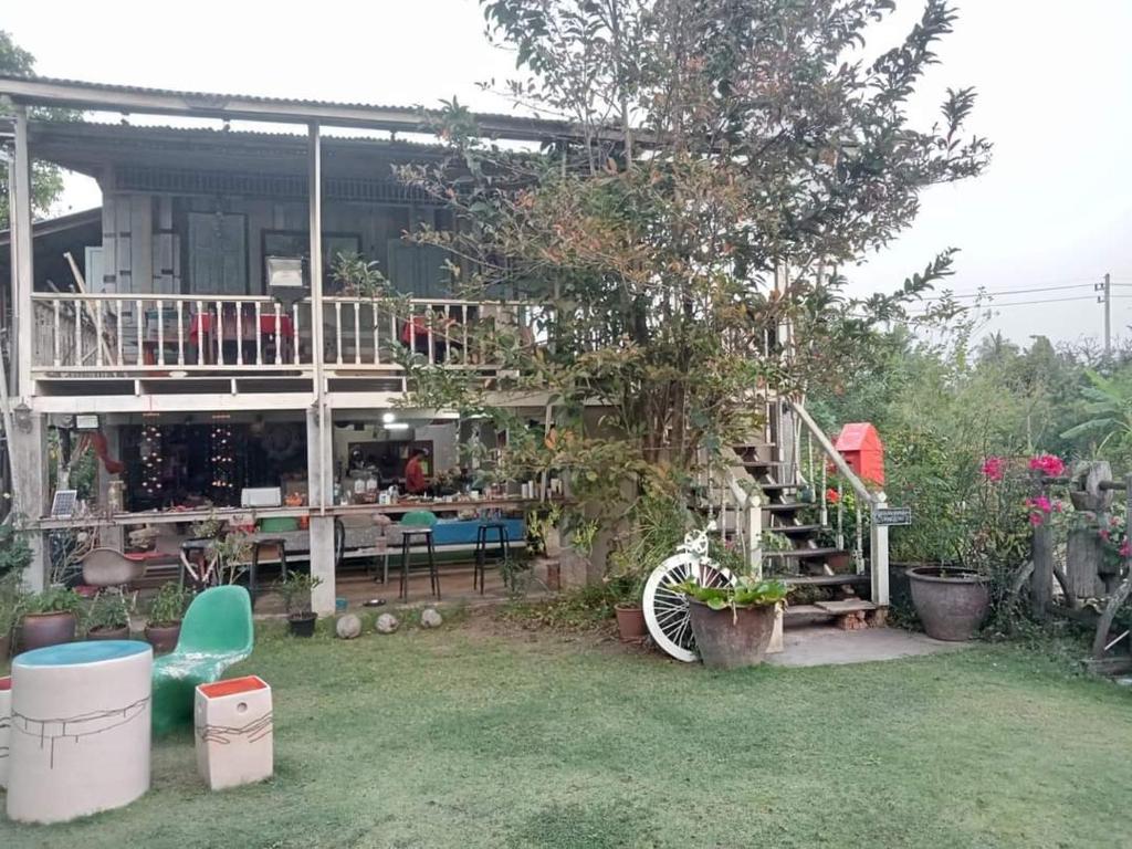 um jardim com uma casa com um deque e um pátio em นิทานคำกลอน 2 Nithankumkon 2 em Amphawa