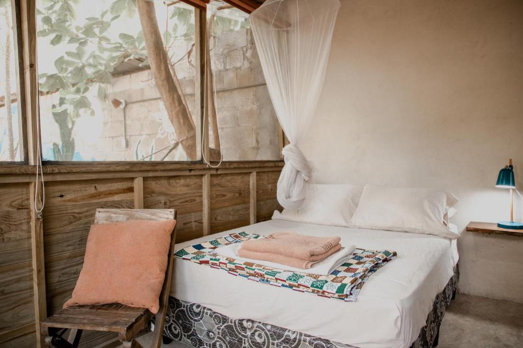a bedroom with a bed with a chair and a window at Casa Austera in El Paredón Buena Vista