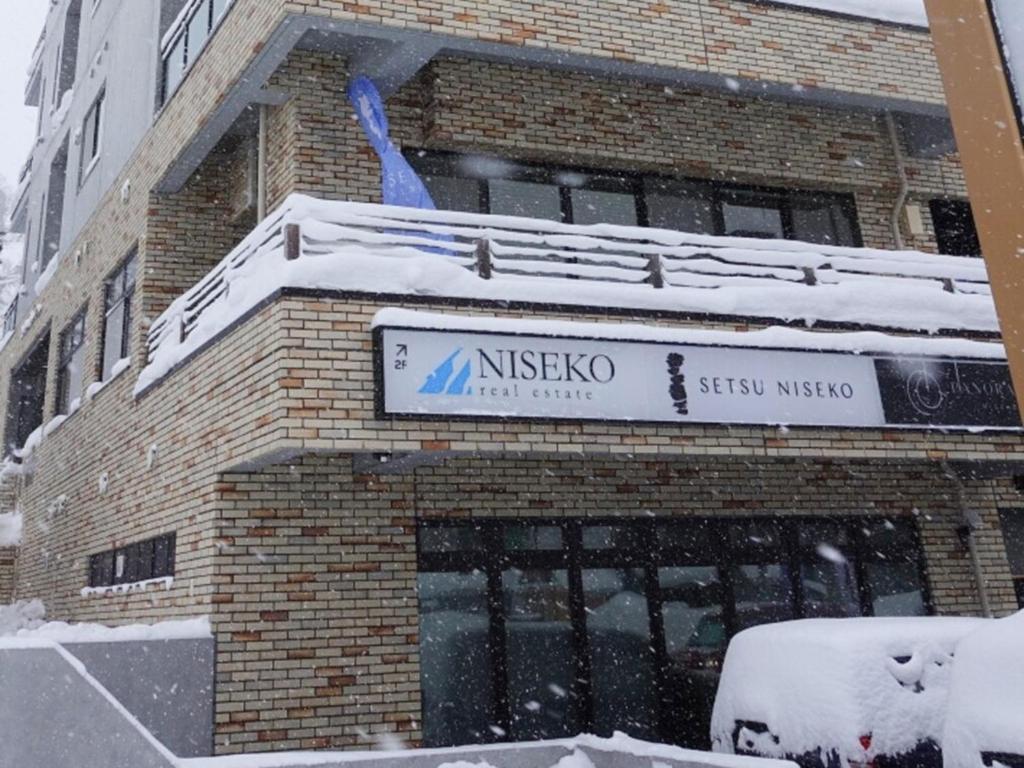 a building with a snow covered sign on top of it at Mountainside Palace in Niseko
