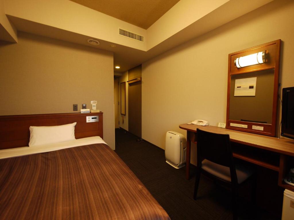 網走市にあるホテルルートイン網走駅前のベッドとデスクが備わるホテルルームです。