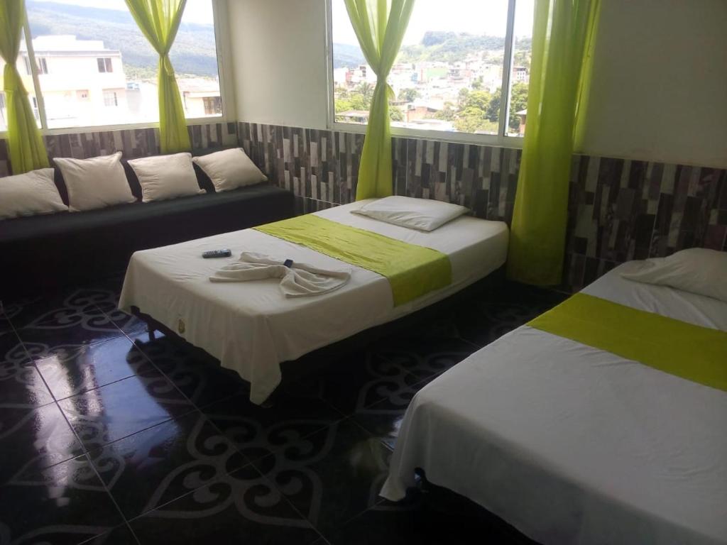 een kamer met 2 bedden, een bank en ramen bij Hotel Luis Ángel in Mocoa