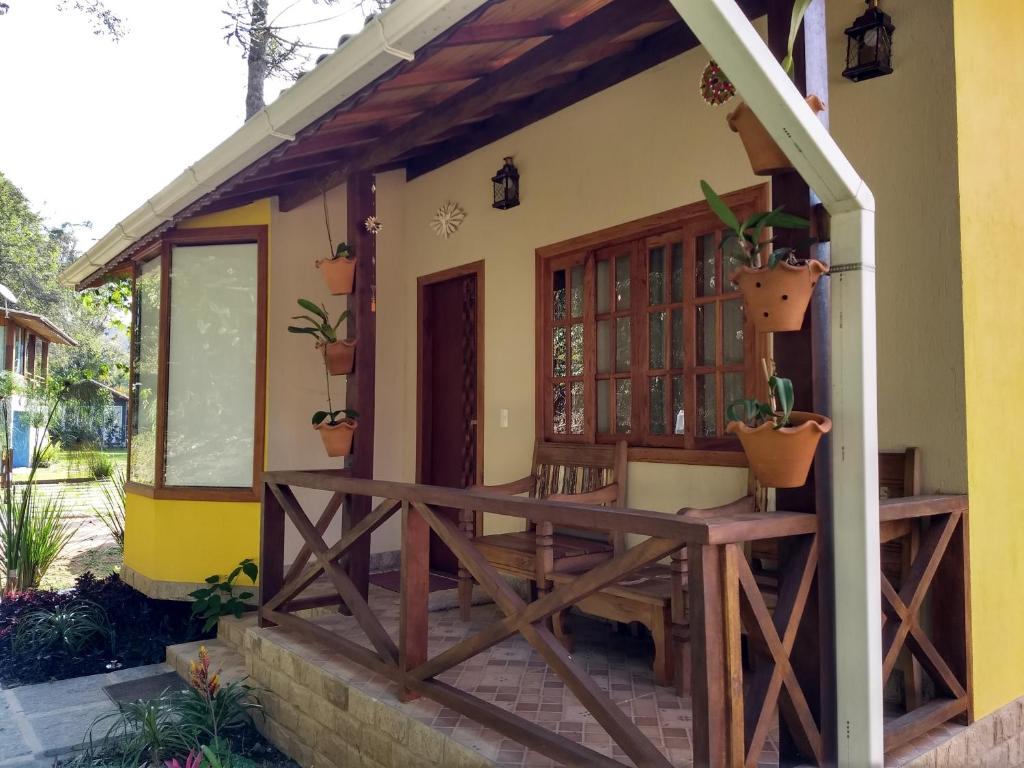 um alpendre de uma casa com vasos de plantas em Chalés das Orquídeas em Visconde de Mauá