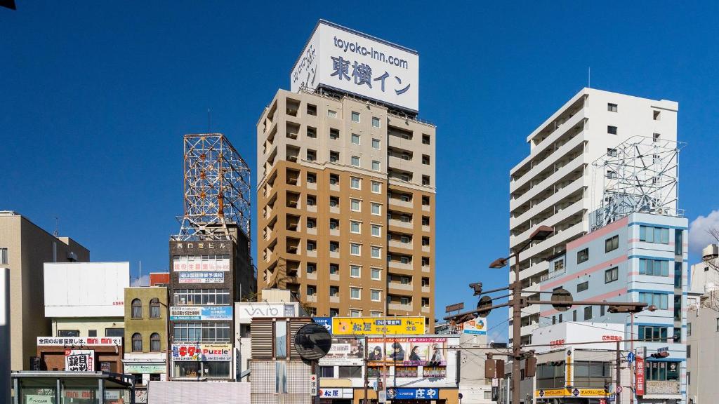 Un palazzo alto con un cartello sopra. di Toyoko Inn Okayama eki Nishi guchi Hiroba a Okayama