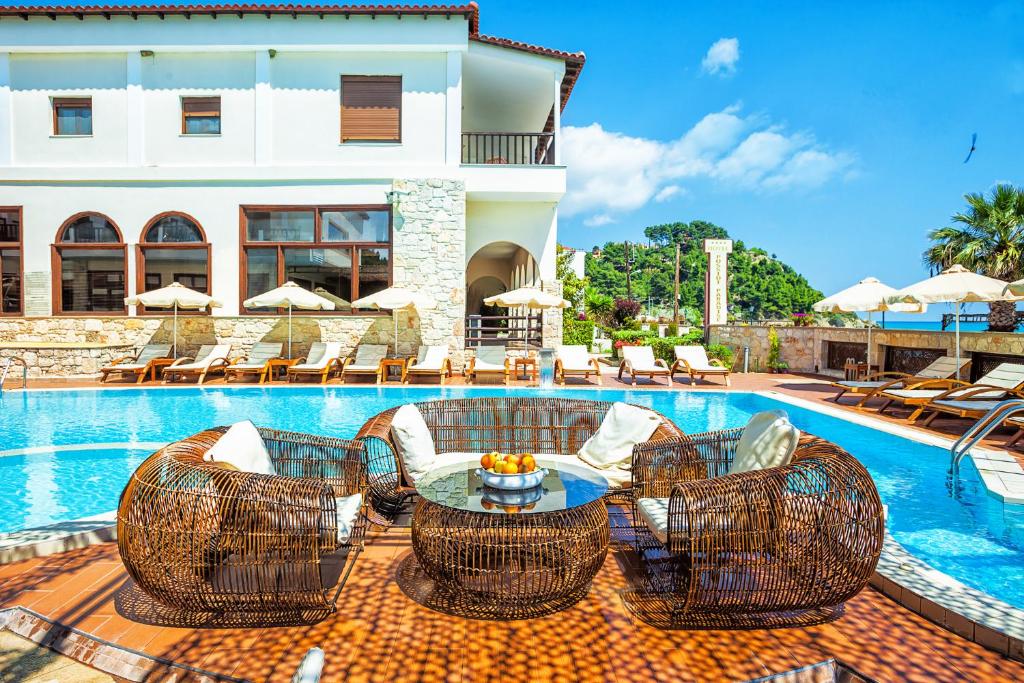 a resort with a swimming pool with chairs and a table at Xenios Possidi Paradise Hotel in Possidi