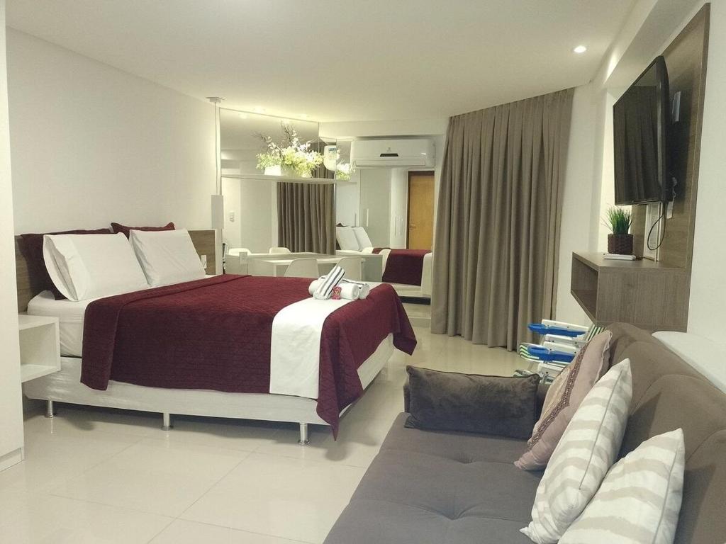 Habitación de hotel con cama y sofá en Nomar X - Lindo Apartamento à 50MTS mar, en João Pessoa