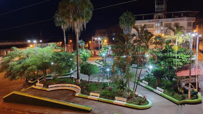 a park with trees and benches in a city at night at HOSTAL FRILIM in La Merced