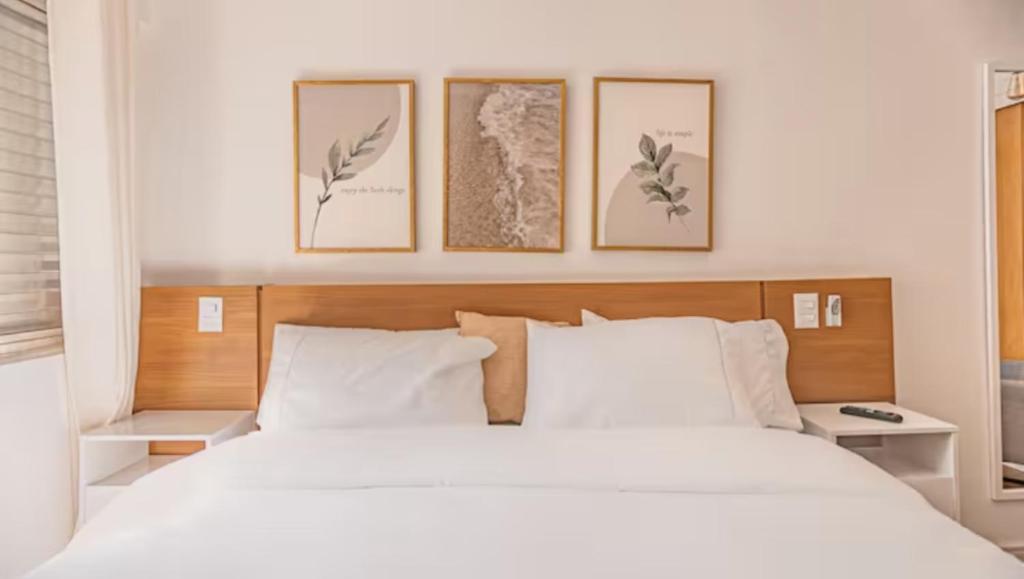 a bedroom with a white bed with four pictures on the wall at Castelli Studios centro SP in Sao Paulo