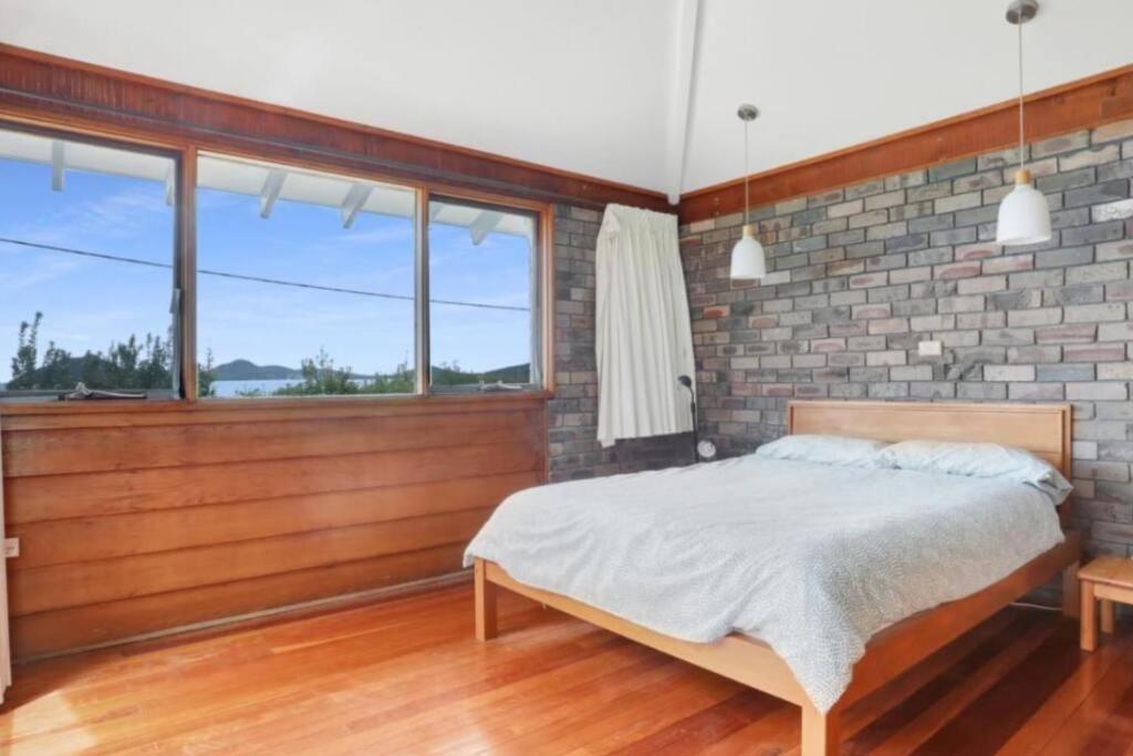 a bedroom with a bed and a brick wall at Seaside Serenity Getaway in Hawks Nest