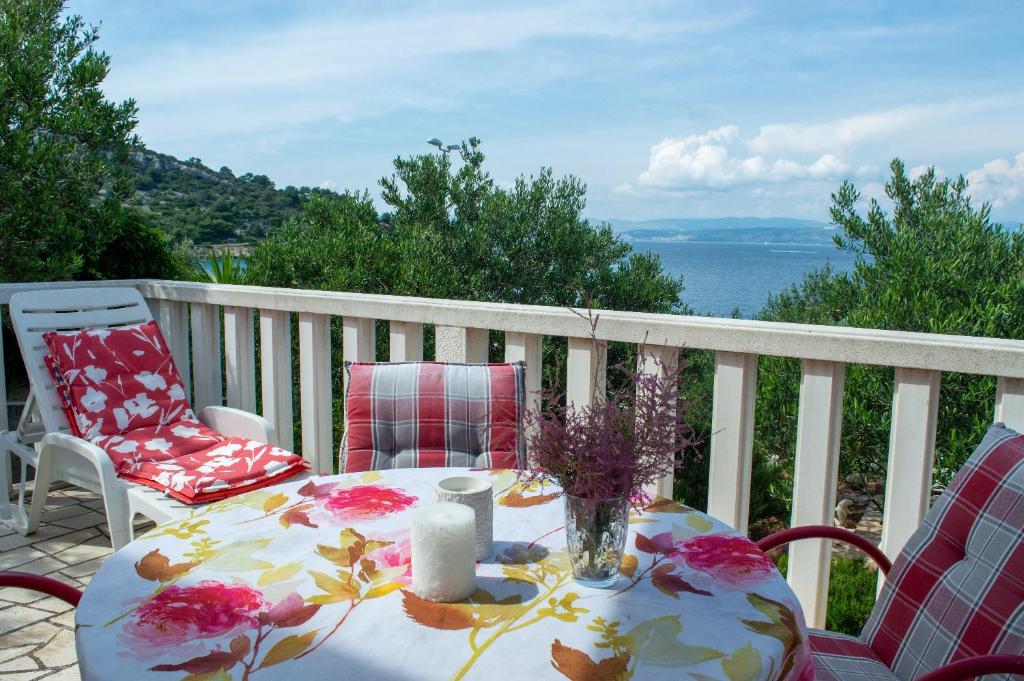 een tafel en stoelen op een balkon met uitzicht op het water bij Apartment Ela - very close to beach in Rogač