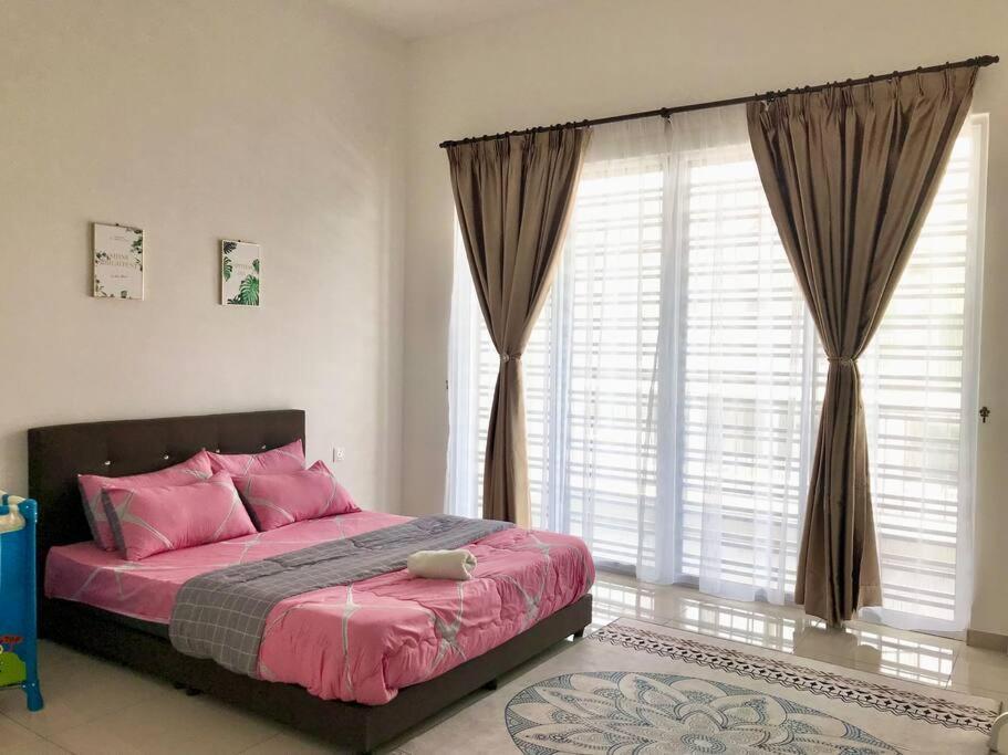 - une chambre avec un lit doté d'oreillers roses et de fenêtres dans l'établissement Cikgu I&S Homestay, à Jitra